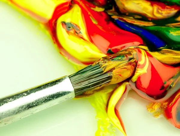 Colored paint mixed on palette. Dirty brush in the foreground. — Stock Photo, Image