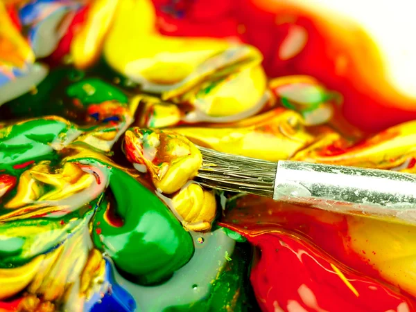 Colored paint mixed on palette. Dirty brush in the foreground. — Stock Photo, Image