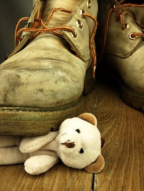 Teddy bear crushed by a heavy, old military boot. clipart
