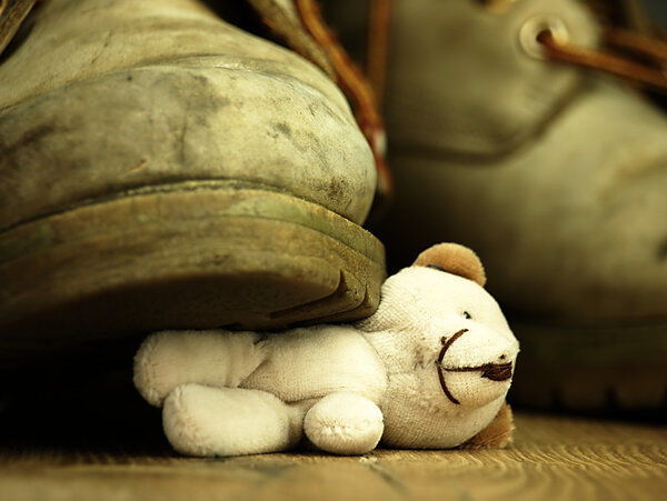 Teddy bear crushed by a heavy, old military boot.
