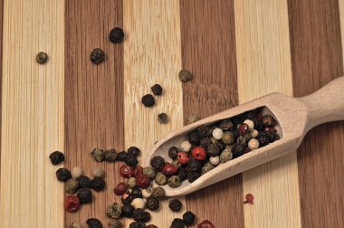 Bir ahşap tahta üzerinde renkli biber taneleri.