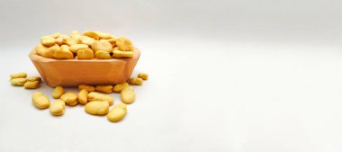 Geniş Fasulye, ayrıca Fava veya Windsor Fasulyesi olarak da bilinir. Beyaz arka planda ahşap kasede. Boşluğu kopyala