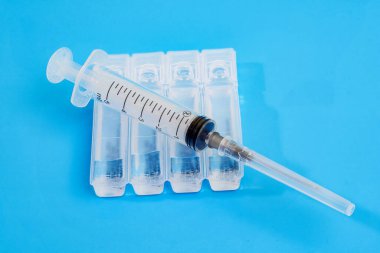 Mavi arka planda plastik kullan-at şırınga ve plastik ampullerin üst görünümü