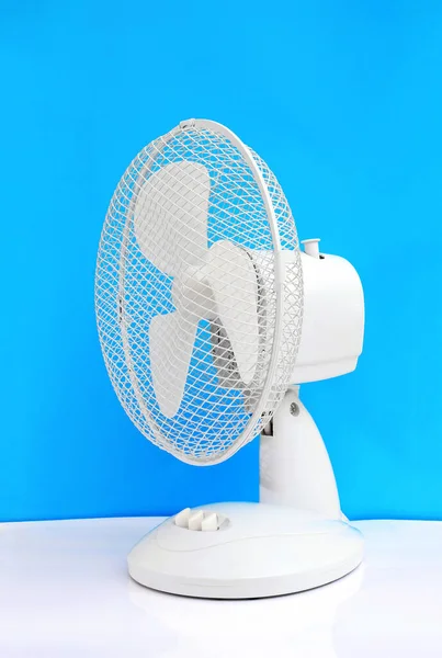 white table oscillating fan on blue background