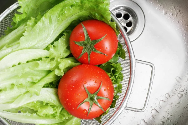 Kevaşe içinde yıkandıktan sonra taze marul yaprakları ve domateslerin üst görüntüsü