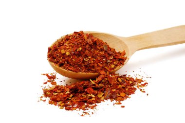 Beyaz arka planda izole edilmiş ahşap kaşıkta kurutulmuş kırmızı biber taneleri, geniş bir alan.