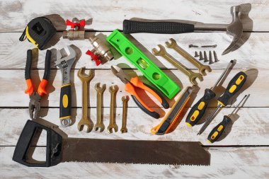 Top view of various handyman tools on wooden table with hard light and shadow, flat lay.
