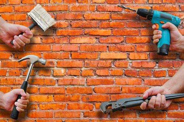 hands holding tools on brickwall background, copy space
