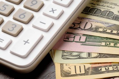 Hesap makinesi ve dolar banknotlarına yakın plan
