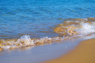 Kumsalda kumların üzerinde süzülen deniz dalgalarına yakın çekim