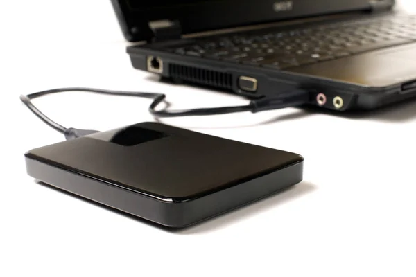 beyaz arkaplanda dizüstü bilgisayara bağlı harici usb diski