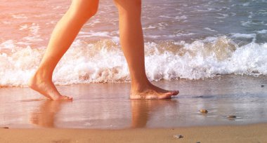 Sahilde çıplak ayakla yürüyen bir adam su kenarında, tonlu, güneş ışığı etkisi