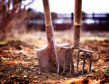 Bahar bahçesindeki toprakta kürek ve yaba, sığ alan derinliği, tonlama, lomografi.