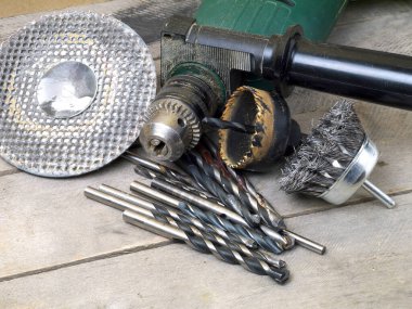 matkap ve eklentiler - tel fırça, delik testeresi, öğütme çemberi ve ahşap masa üzerindeki çeşitli parçalar, üst görünüm