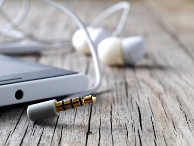 Kulaklığın fişi çekilmiş mini-jack akıllı telefon bağlantısının ahşap tahta, makro, sığ alan derinliği