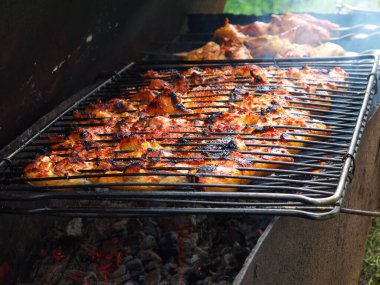 Kömürde menteşeli ızgarada hafif yanmış tavuk.