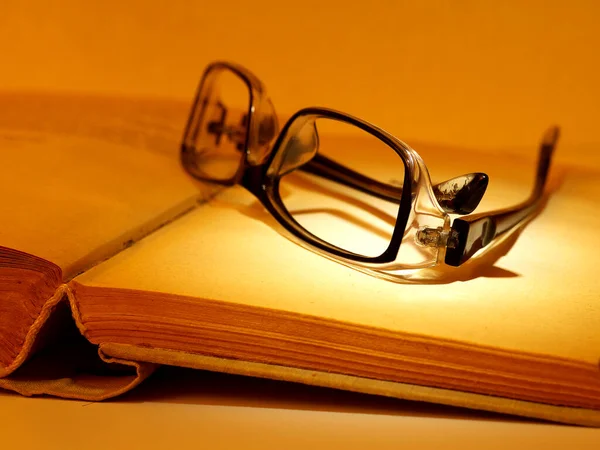 reading glasses on old book, cloth hardcover, closeup, shallow depth of field, toned in yellow