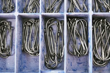 Top view of tackle box with fishing hooks. Fishing hooks in box sections. Macro of fishhooks. clipart
