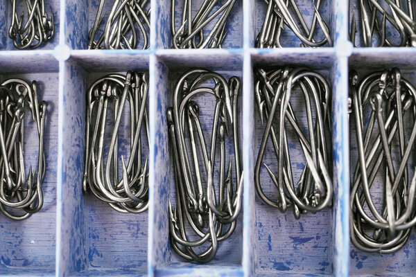 Top view of tackle box with fishing hooks. Fishing hooks in box sections. Macro of fishhooks.