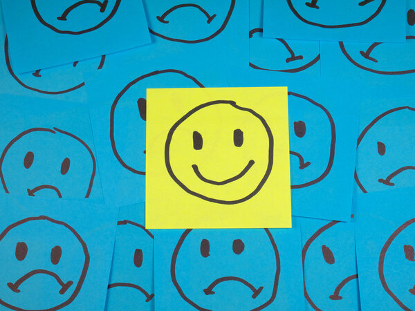Позитивный смайлик на липкой ноте на грустных лицах