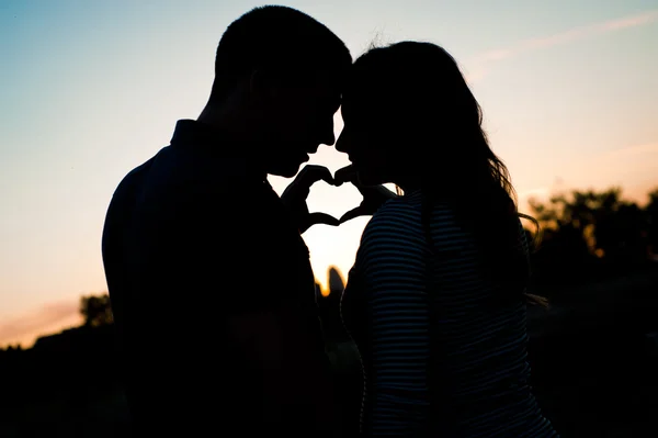 Dos manos hacen un corazón juntas al atardecer —  Fotos de Stock