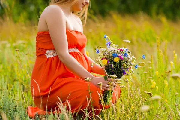 Беременная женщина на открытом воздухе с цветами — стоковое фото