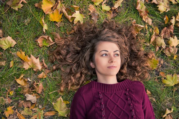 Jong meisje met bladeren in de herfst — Stockfoto