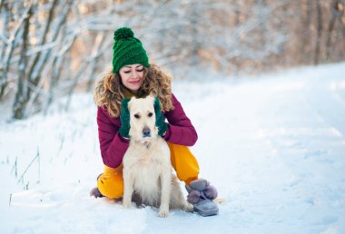 Kışın açık havada köpeğiyle Golden Retriever 'a sarılan genç bir kızın görüntüsü. Evcil hayvan. Köpekle oynayan bir kadın. Yakın plan portre