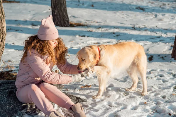 Owner helps her lovely dog Golden retriever to clear the paws. The dog\'s paws freeze in winter and the snow is clogged. A girl warms the paws of a dog who is frozen. Friendship, pet and human. Care about dog in winter