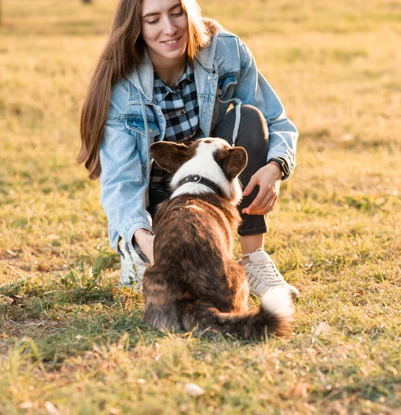 Jeune femelle étreignant son chien gallois Corgi dans le parc du printemps — Photo