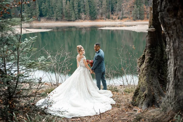 Brud och brudgum vid bröllopsceremoni på den vackra sjön bakgrund. Stockbild
