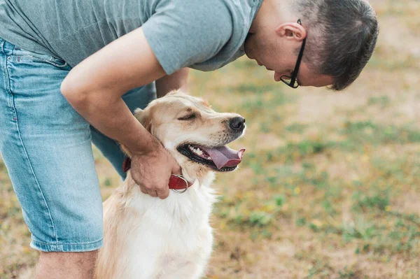 Golden retriever perro sentado con el propietario al aire libre — Foto de Stock