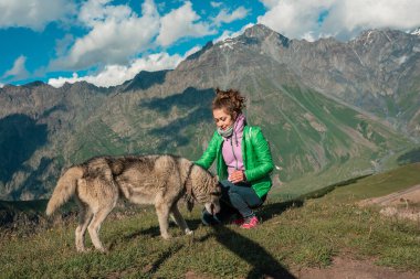 Genç dişi ve köpek birlikte dağ manzarasının tadını çıkarıyorlar.