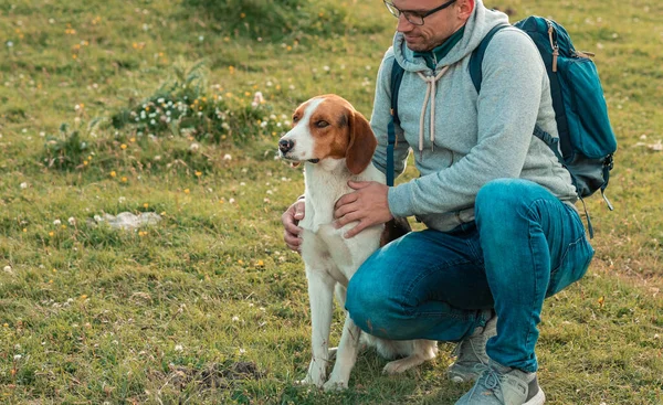 Молодой мужчина с собакой вместе наслаждается горным пейзажем — стоковое фото