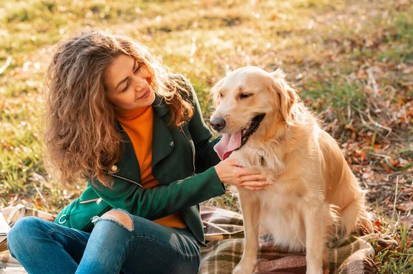 Ung lockig kvinna med sin hund Golden retriever omfamna utomhus — Stockfoto