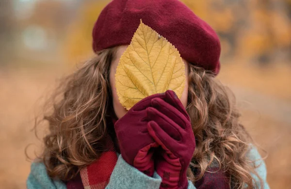 Beautiful girl closeup on autumn leaves and looks at the camera with a smile — Stock Photo, Image