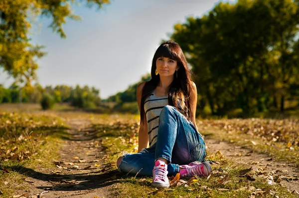 Young pretty woman sitting in the autumn park — Stock Photo, Image