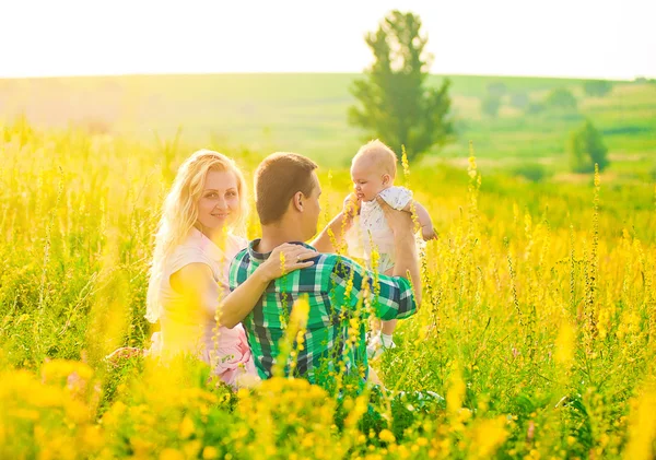 Feliz familia joven sosteniendo un bebé oloroso de 3-4 meses de edad —  Fotos de Stock