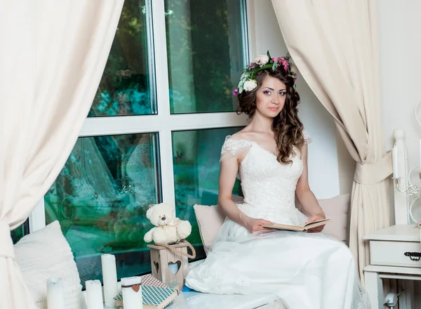 Schöne brünette Braut mit einem Buch. Hochzeitsinterieur — Stockfoto