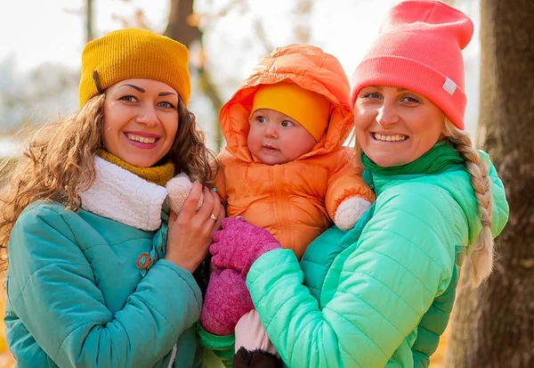 Happy friends holding a smilling  7 month old baby — Stock Photo, Image