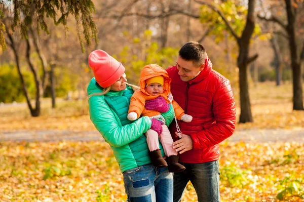 Familia joven en el parque disfrutando del otoño con el niño —  Fotos de Stock