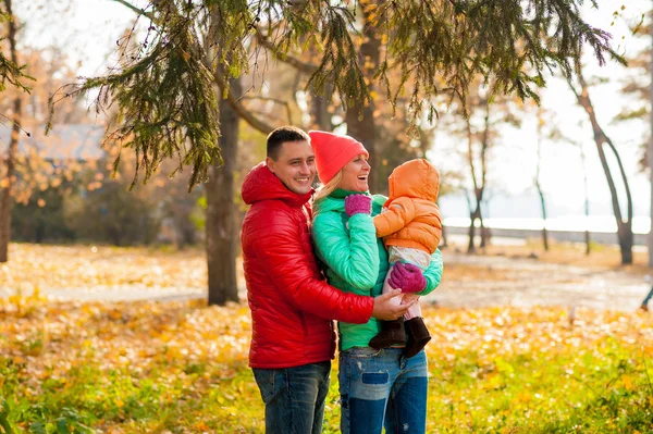 Familia joven en el parque disfrutando del otoño con el niño —  Fotos de Stock