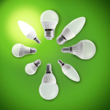 Parlayan Led enerji tasarruflu ampul bir elinde yeşil bir arka plan üzerinde