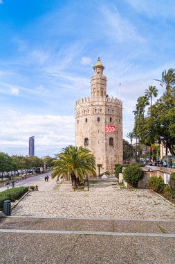 Seville, İspanya; 7 Şubat 2021: Torre del Oro önü ve Guadalquivir nehri boyunca gezinti alanı. Arkasında Torre Sevilla gökdeleni olan sembolik bir yer..