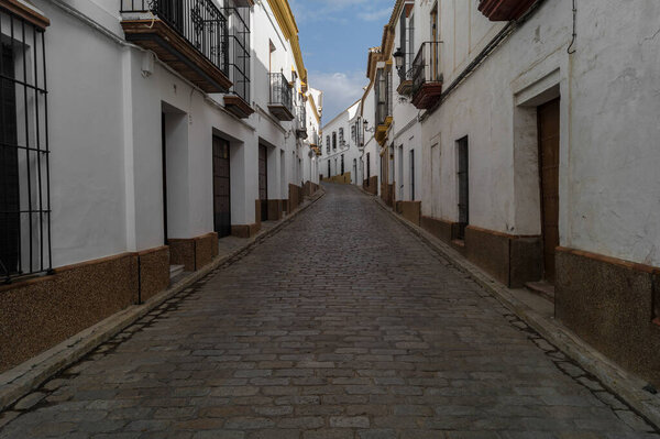 Alley or narrow street with traditional cobblestone floor and white-walled houses in the famous town of Carmona (Seville, Spain). Empty and quiet street in a town with the typical Andalusian houses.