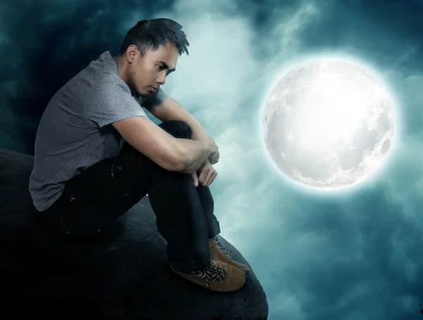 Fantasy world - young man sitting at a full moon — Stock Photo, Image