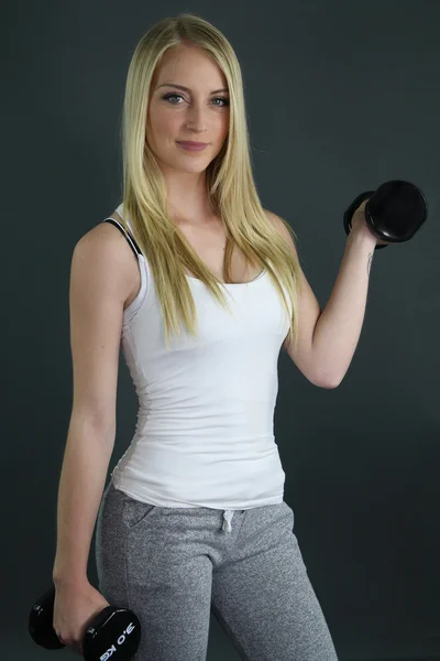 Beautiful blonde girl holding a dumbbell — Stock Photo, Image