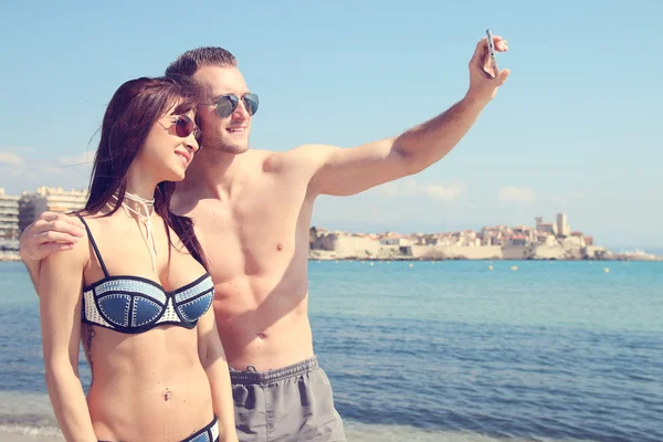 Casal atraente fazendo uma selfie em frente à praia — Fotografia de Stock