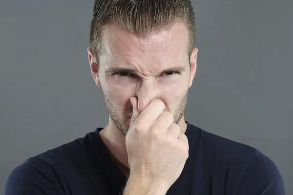 Hombre pellizcándose la nariz sobre un fondo gris — Foto de Stock