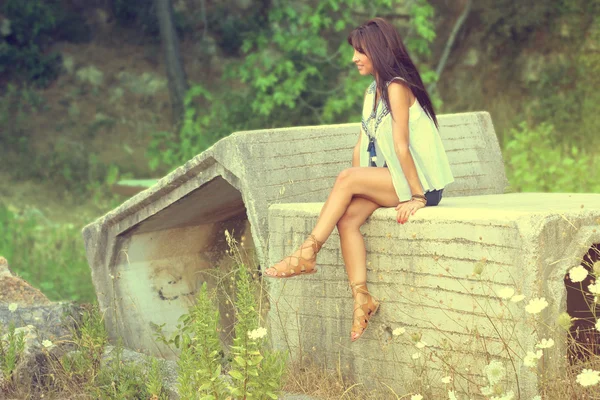 Beautiful brunette sitting on a stone — Stock Photo, Image